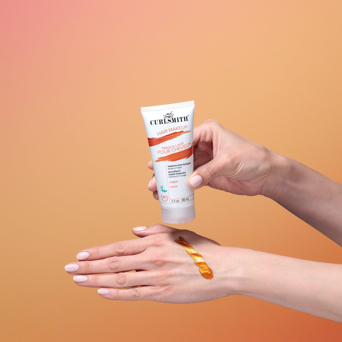 Hand holding a tube of Curlsmith hair mask against an orange gradient background