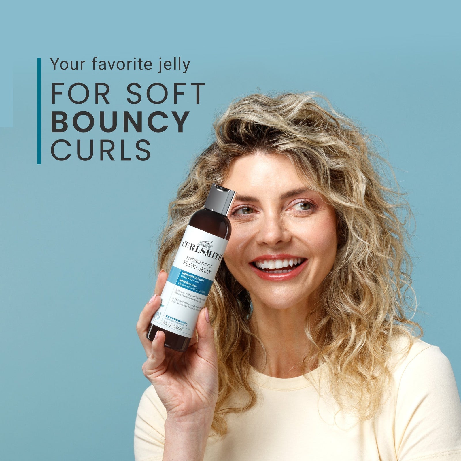Woman holding a bottle of product with text about soft bouncy curls on a blue background