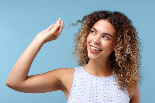 Woman with curly hair in front of blue background