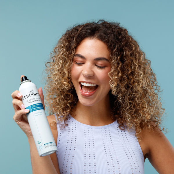 Curly Woman with Curlsmith Hairspray in front of blue background