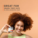 Woman with curly hair holding a jar of hair product against an orange background