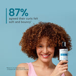 Woman holding a bottle of product with text about curl satisfaction on a blue background