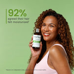 Woman holding a bottle of shampoo with a green background and text about hair moisturization.