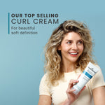 Woman holding a bottle of curl cream against a blue background